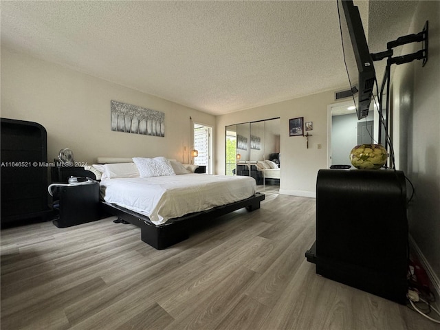 bedroom featuring wood-type flooring, a closet, and a textured ceiling