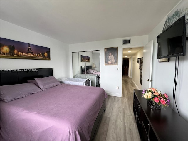 bedroom with light hardwood / wood-style floors and a closet