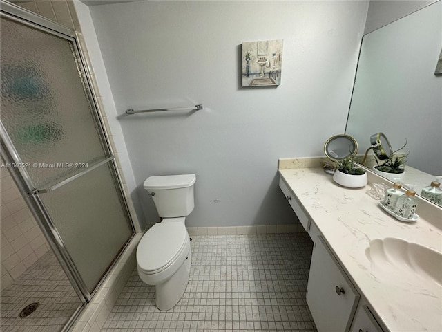 bathroom with tile patterned flooring, an enclosed shower, vanity, and toilet