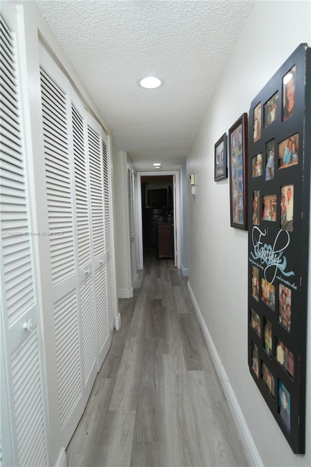 corridor featuring a textured ceiling and hardwood / wood-style flooring