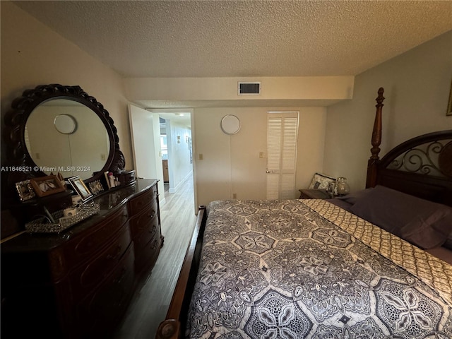 bedroom with a textured ceiling and hardwood / wood-style floors