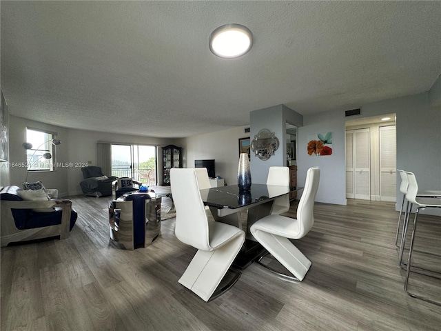 dining space featuring wood-type flooring and a textured ceiling