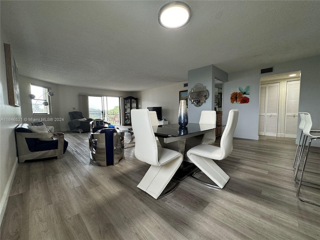 dining room with a textured ceiling and wood-type flooring