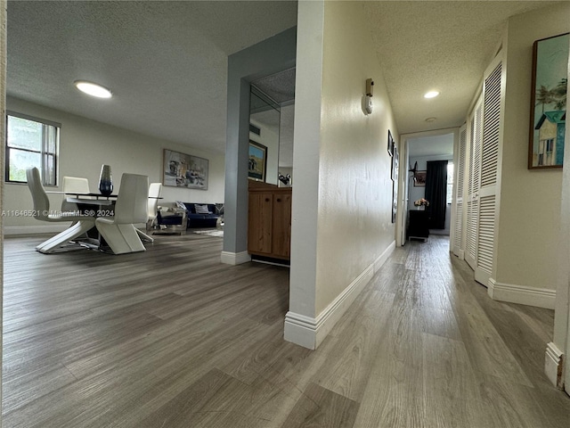 corridor with a textured ceiling and hardwood / wood-style flooring