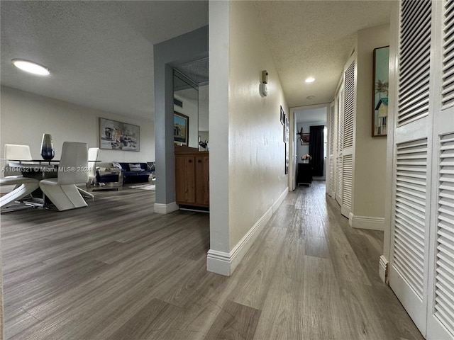 hallway with a textured ceiling and wood-type flooring