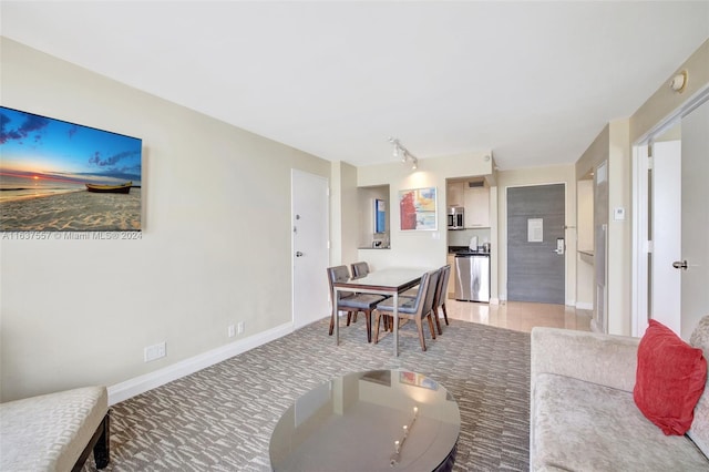 dining room featuring track lighting, light colored carpet, and baseboards