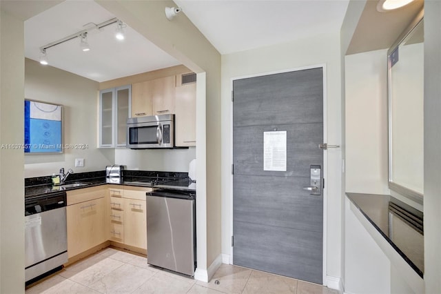 kitchen featuring visible vents, glass insert cabinets, stainless steel appliances, light brown cabinetry, and a sink