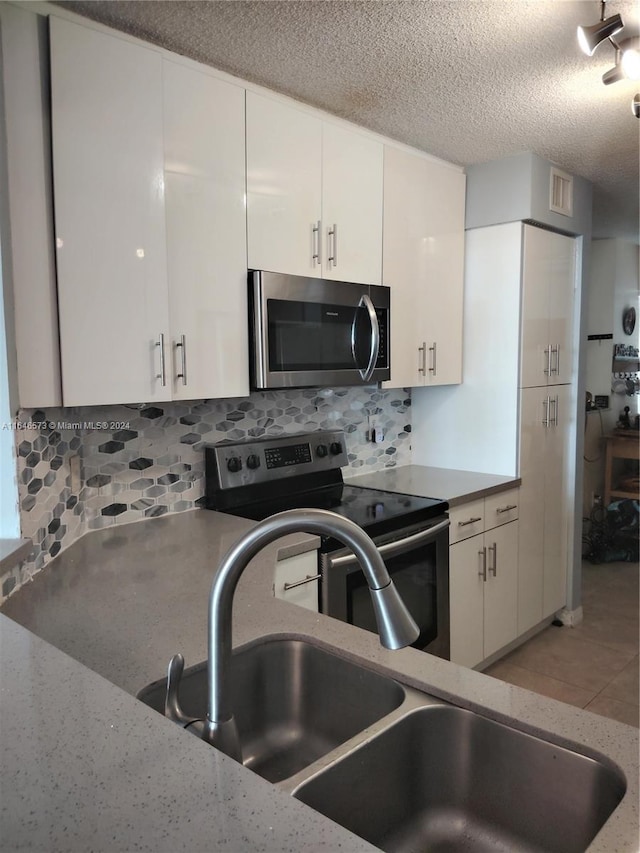 kitchen with white cabinets, decorative backsplash, and stainless steel appliances