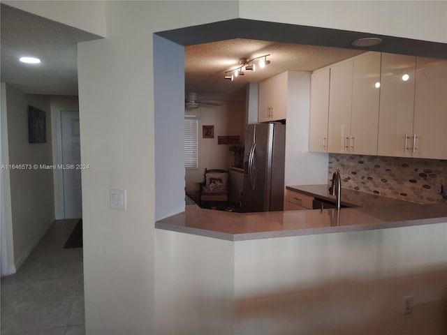 kitchen with stainless steel fridge with ice dispenser, light tile patterned floors, a textured ceiling, sink, and kitchen peninsula