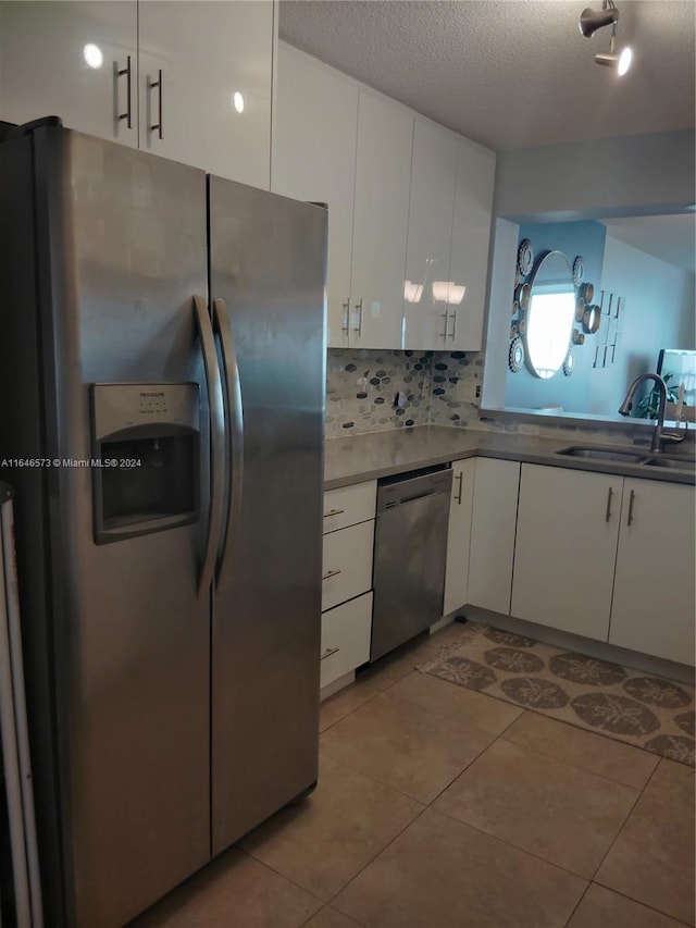 kitchen featuring stainless steel appliances, white cabinets, decorative backsplash, a textured ceiling, and sink