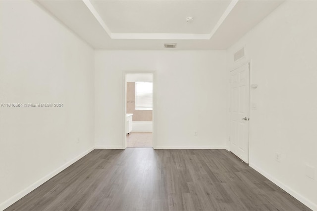 unfurnished room with dark wood finished floors, a raised ceiling, baseboards, and visible vents