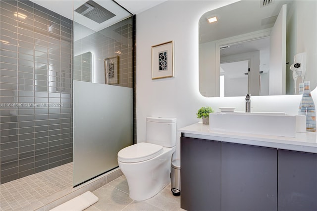 bathroom with tile patterned flooring, vanity, tiled shower, and toilet