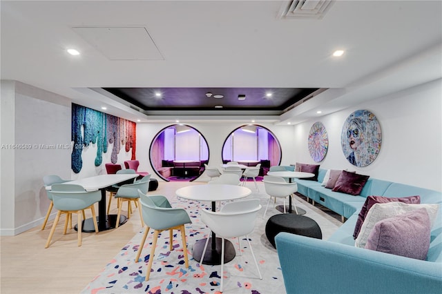 game room with a raised ceiling and light hardwood / wood-style flooring