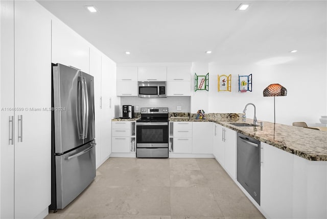 kitchen with stainless steel appliances, sink, kitchen peninsula, and white cabinets