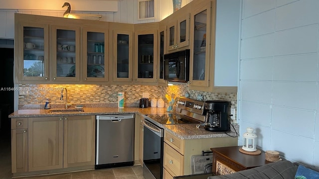 kitchen featuring appliances with stainless steel finishes, tasteful backsplash, sink, light stone counters, and light tile patterned floors