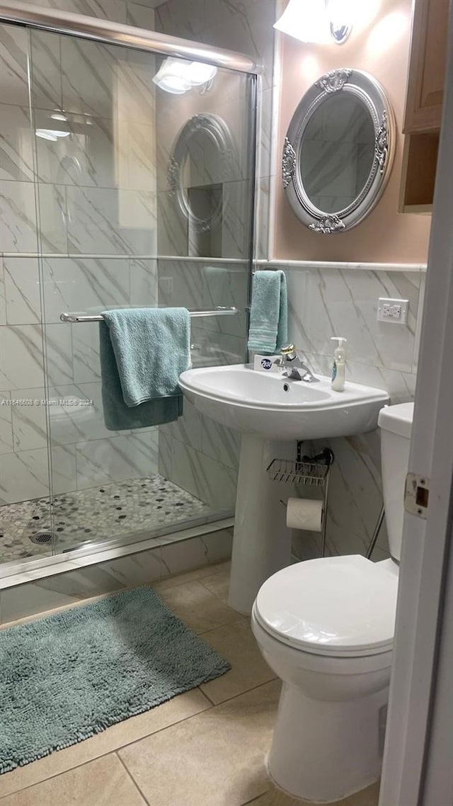 bathroom featuring backsplash, tile patterned flooring, a shower with shower door, tile walls, and toilet