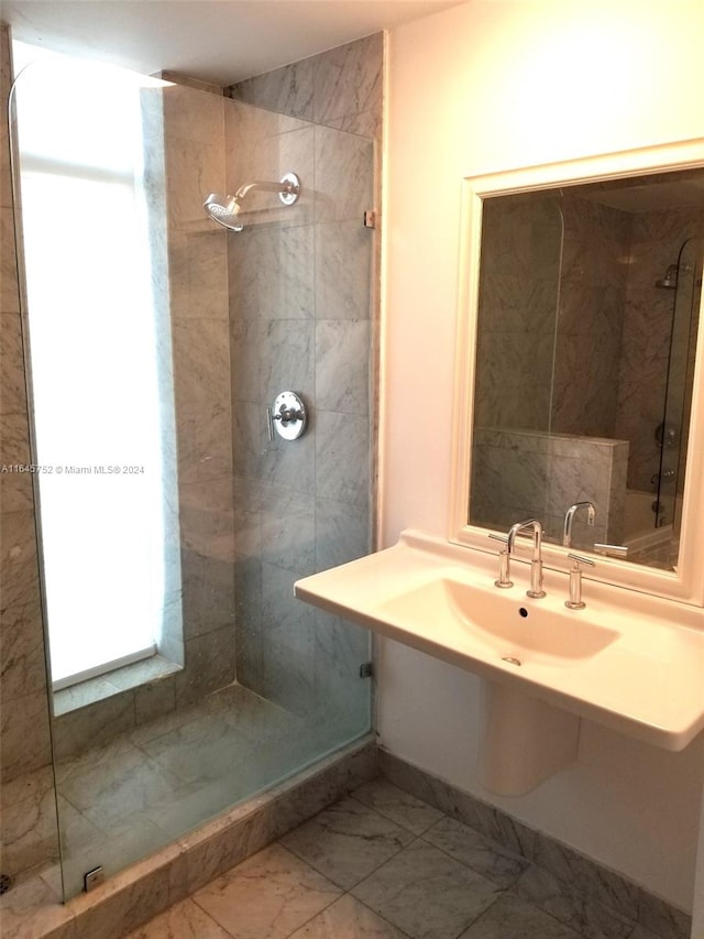 bathroom with tile patterned flooring, tiled shower, and sink