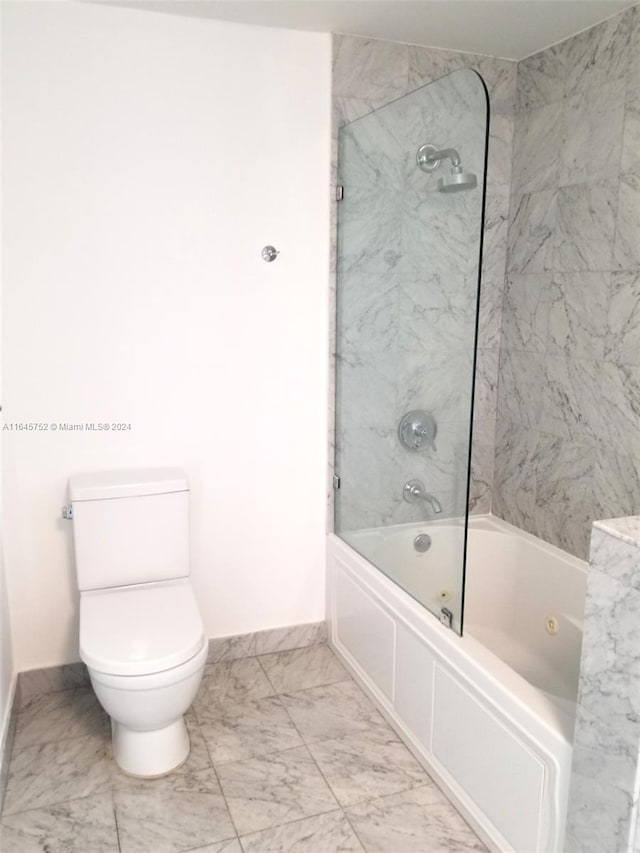 bathroom featuring tile patterned flooring, toilet, and tiled shower / bath