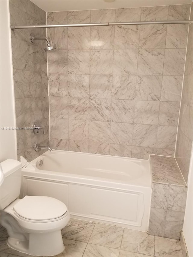 bathroom with tile patterned flooring, toilet, and tiled shower / bath combo