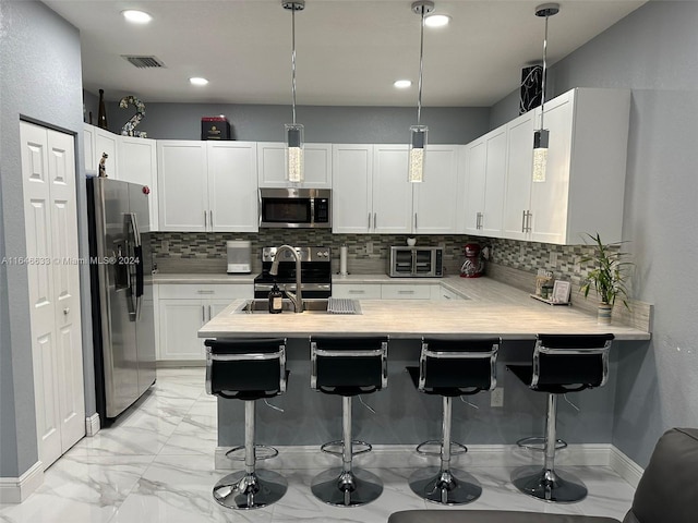 kitchen with backsplash, stainless steel appliances, white cabinetry, a kitchen breakfast bar, and kitchen peninsula