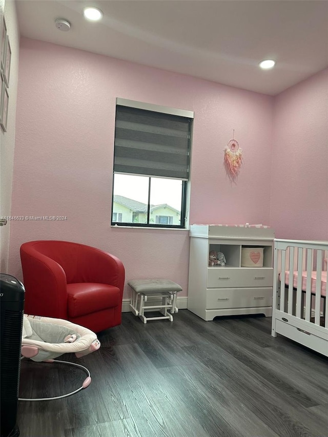 bedroom featuring a crib and dark hardwood / wood-style flooring