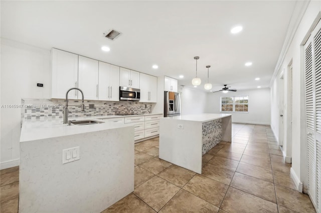 kitchen with stainless steel appliances, decorative backsplash, sink, a center island, and ceiling fan