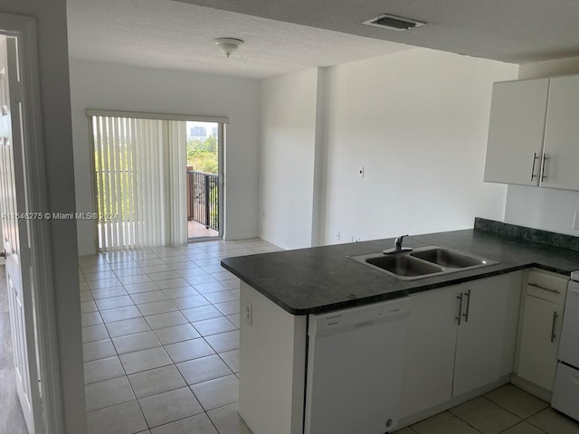 kitchen with sink, white cabinetry, white dishwasher, light tile patterned floors, and kitchen peninsula