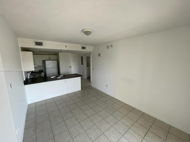 unfurnished living room with sink and light tile patterned floors