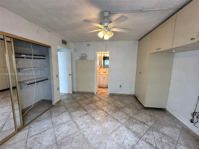 unfurnished bedroom with connected bathroom, a textured ceiling, a closet, ceiling fan, and light tile patterned flooring