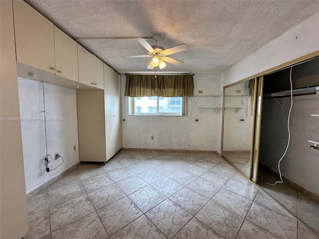 unfurnished bedroom with ceiling fan, a closet, a textured ceiling, and light tile patterned floors