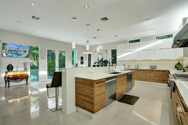 kitchen featuring white cabinetry, pendant lighting, a spacious island, exhaust hood, and appliances with stainless steel finishes