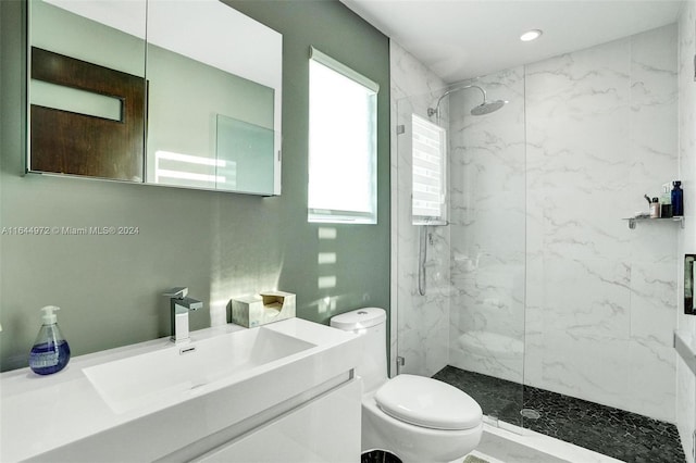 bathroom featuring a tile shower, vanity, and toilet