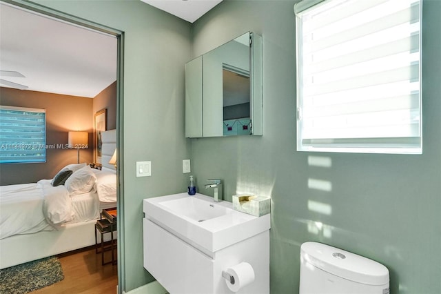 bathroom with ceiling fan, vanity, wood-type flooring, and toilet