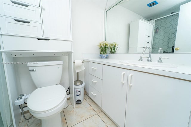 bathroom featuring tile patterned flooring, vanity, tiled shower, and toilet