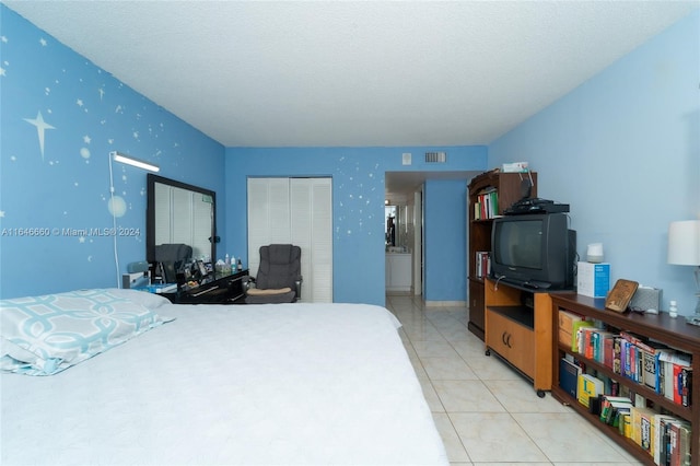 tiled bedroom with a textured ceiling and a closet