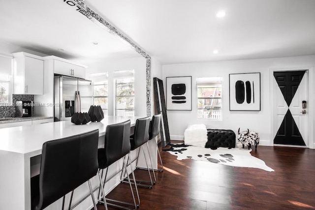 kitchen featuring stainless steel refrigerator with ice dispenser, tasteful backsplash, a healthy amount of sunlight, and white cabinets