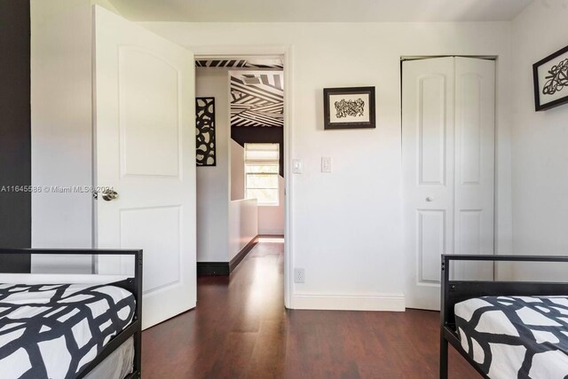 bedroom with dark wood-type flooring and a closet