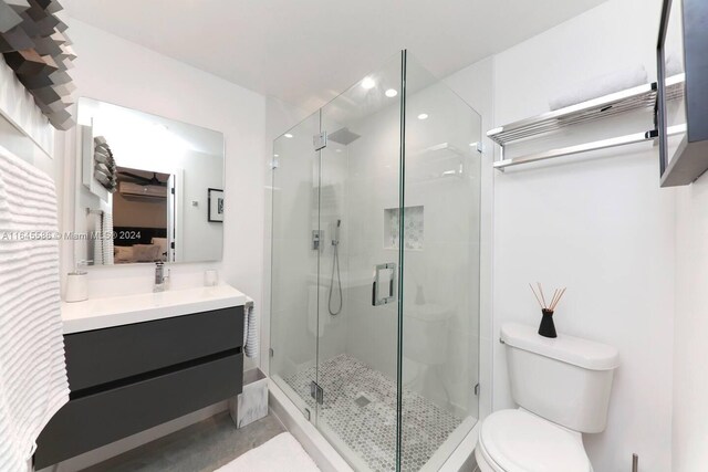 bathroom with an enclosed shower, vanity, and toilet