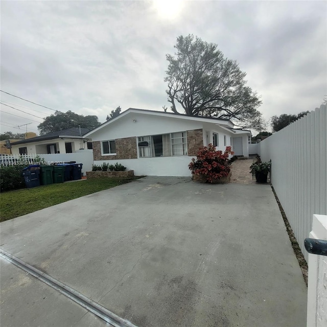 view of front of home featuring stone siding, fence, and driveway