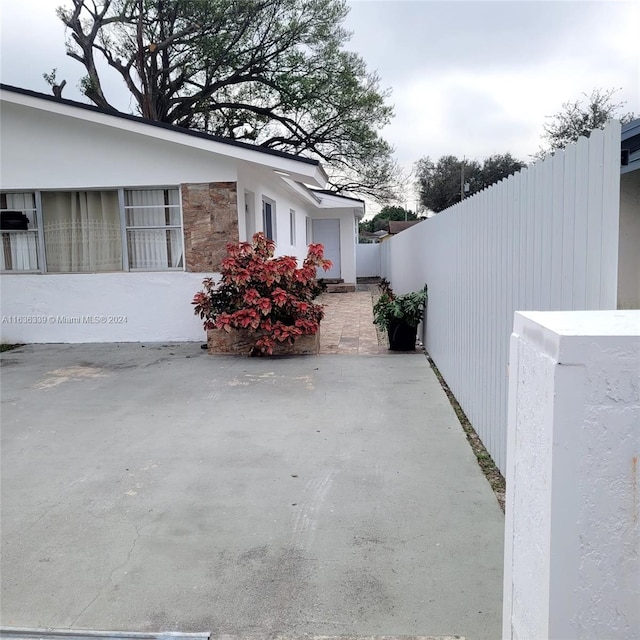 view of side of property featuring stone siding, a patio area, and fence