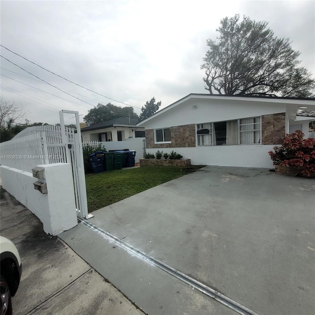 single story home featuring stone siding, a fenced front yard, a gate, and a front yard