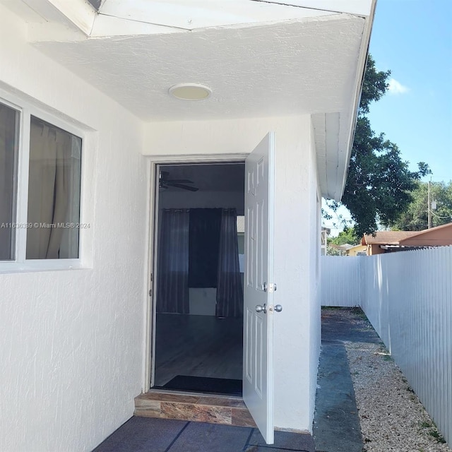 property entrance featuring fence and stucco siding