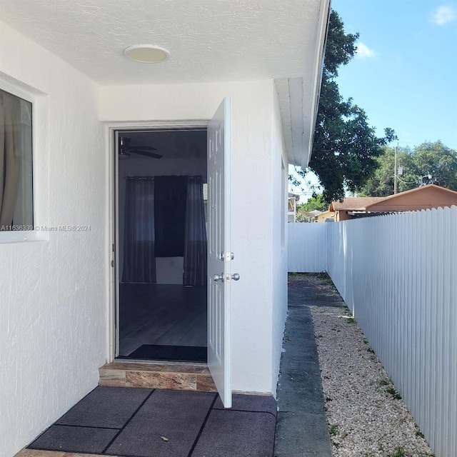 entrance to property with fence and stucco siding