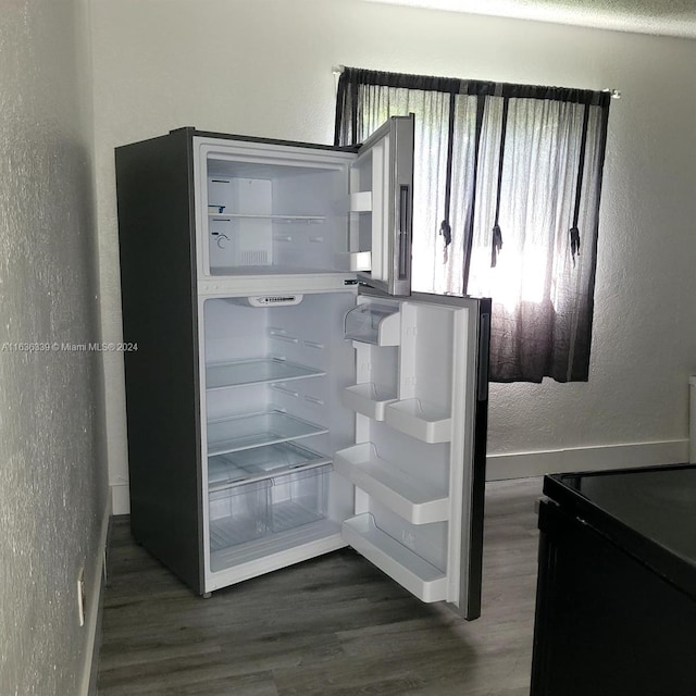 interior space featuring a textured wall, dark wood finished floors, electric range, and fridge