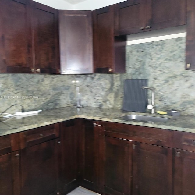 kitchen featuring a sink, backsplash, and light stone countertops