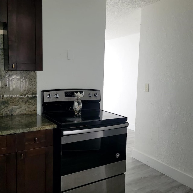 kitchen featuring dark countertops, electric stove, dark brown cabinetry, and baseboards