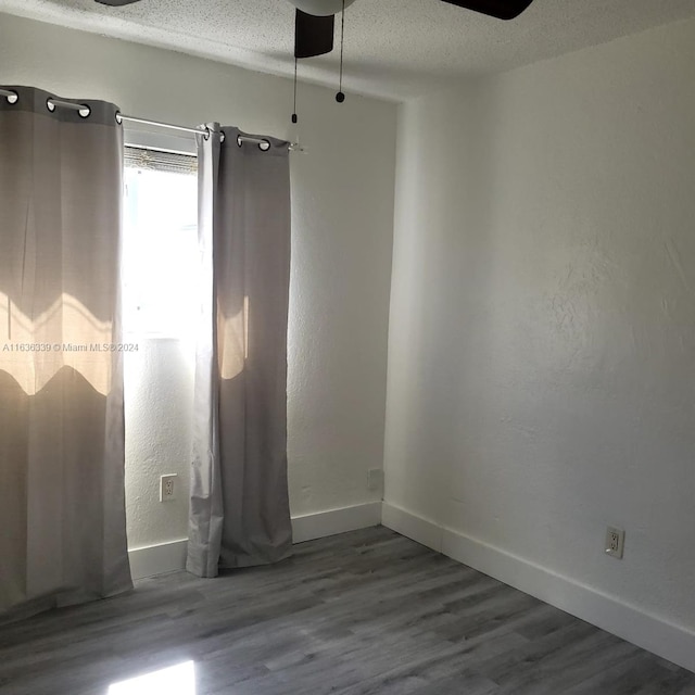 spare room featuring a textured ceiling, wood finished floors, a ceiling fan, and baseboards