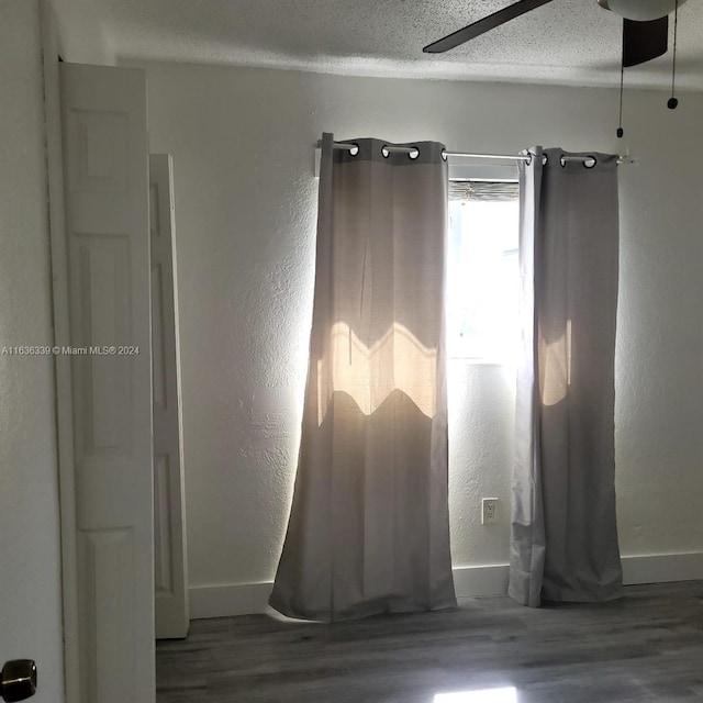 empty room with ceiling fan, baseboards, a textured ceiling, and wood finished floors