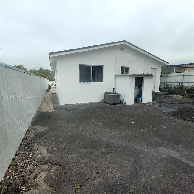 back of house featuring central air condition unit, fence, and stucco siding