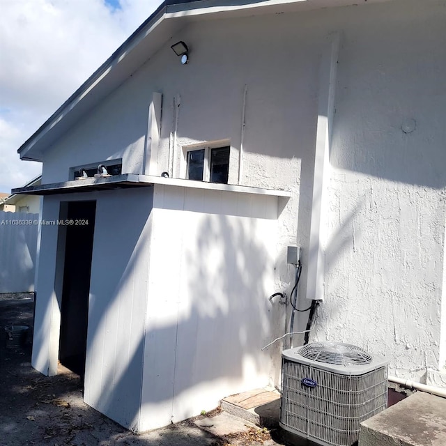 view of side of property with central AC unit and stucco siding